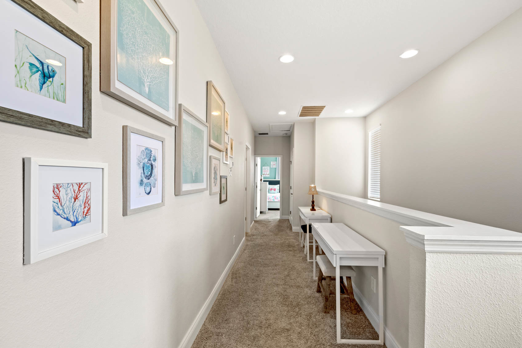 upstairs white hallway with frames on wall
